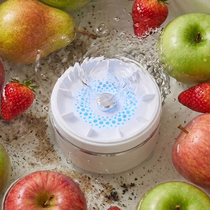 L'appareil PuriEasy allumé au fond d'un récipient rempli d'eau, entouré de pommes et de fraises